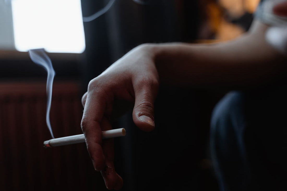 Uomo che fuma una sigaretta, riflettendo sugli effetti negativi del fumo sulla salute sessuale
