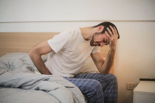 Uomo preoccupato seduto a letto, simbolo del disagio causato dall’eiaculazione precoce e della necessità di combattere l’eiaculazione precoce.