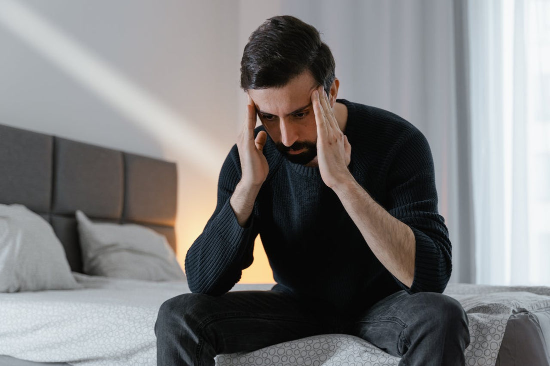 Uomo solo a letto con espressione preoccupata e sguardo rivolto verso il soffitto