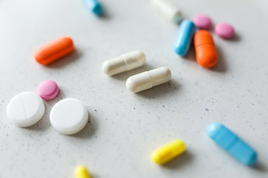 Diversi tipi di pillole su una superficie chiara, tra cui farmaci soggetti a controindicazioni di Tadalafil.